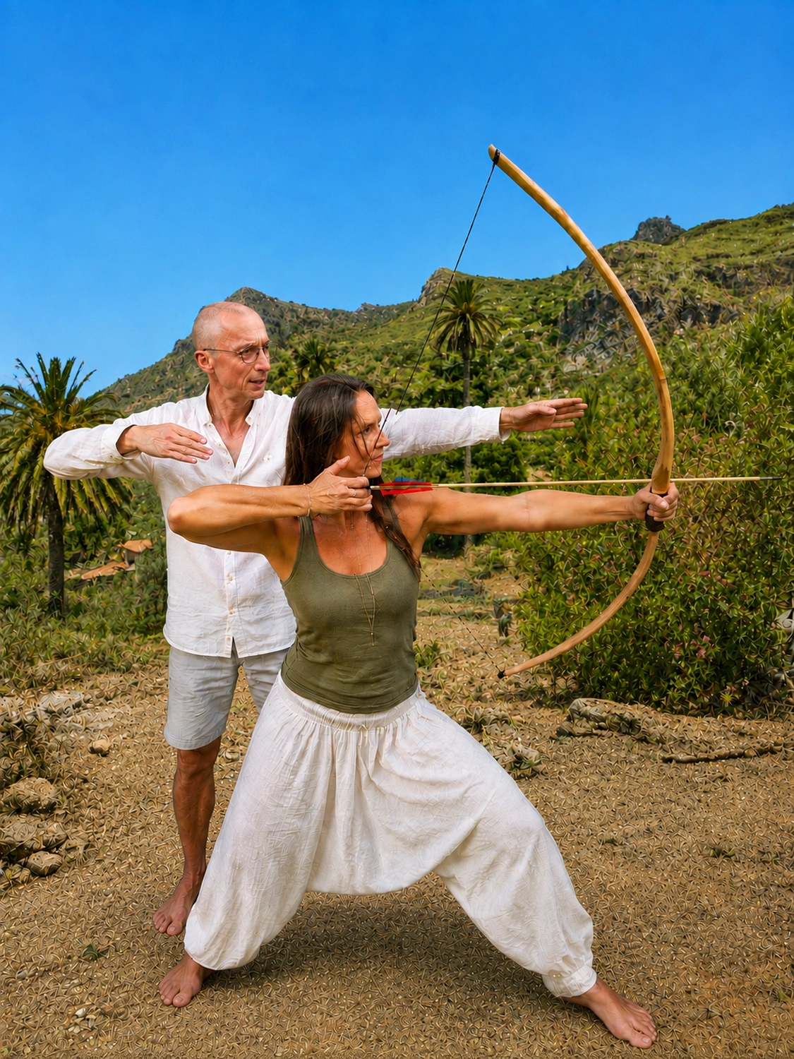 Körperglück -Massage Therapy and Pelvic Floor Training - Wooden tables, chairs, and palm trees on a stone terrace overlooking a black pebble beach and distant sea cliffs under a bright blue sky.